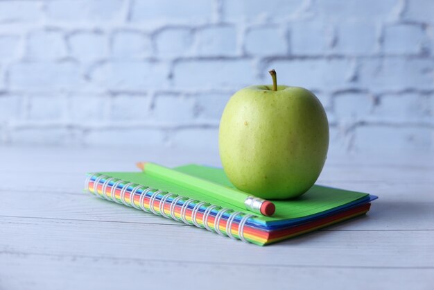 Negro al concepto de escuela con manzana en el bloc de notas en la mesa.