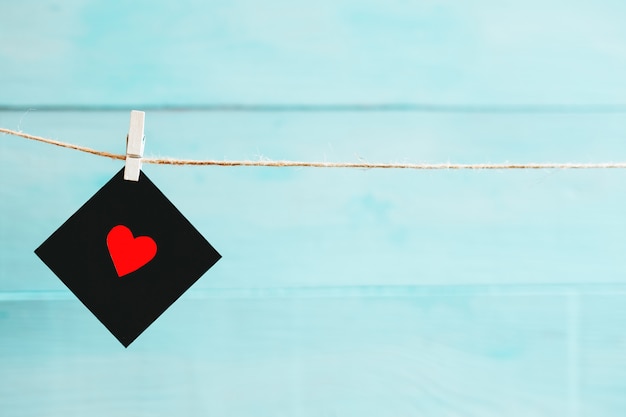 Foto negro en blanco y rojo con su corazón extendido en una cuerda sobre fondo azul. fondo de san valentín