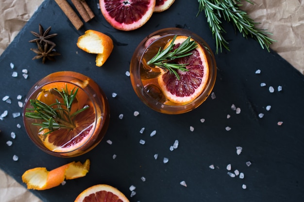 Negroni Cocktail auf Schwarz serviert mit einer Scheibe Orange und Rosmarin.