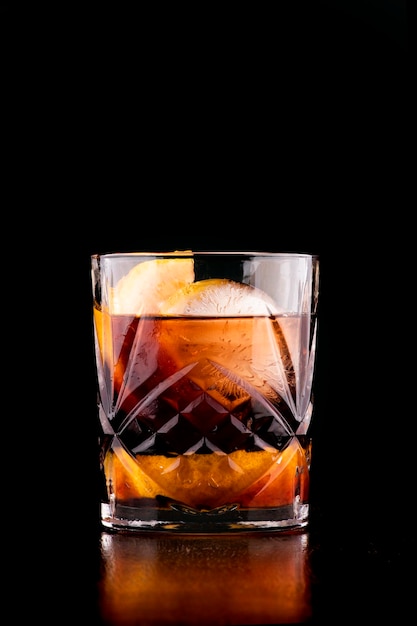 Negroni-Cocktail mit rundem und orangefarbenem Eis auf dunklem Hintergrund