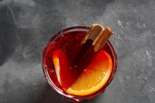 Negroni Cocktail. Rauchiger italienischer Aperitivo mit Gin, Campari, Martini Rosso, Orange und Eiswürfeln, serviert in Glas auf dunkler Steinoberfläche