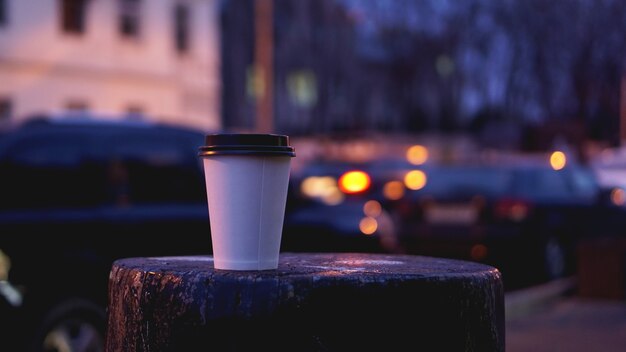 Nehmen Sie Kaffeetasse leeren leeren Kopienraum für Ihren Designtext oder Banner der Marke, heißes Getränk auf Holztisch mit schöner Stadtlichtdekoration weg