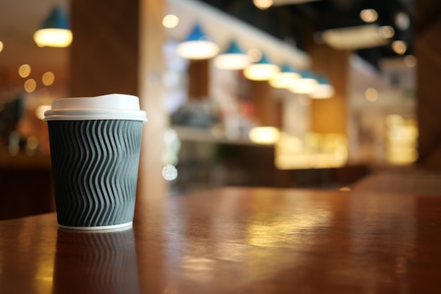 Nehmen Sie Papierkaffeetasse o auf dem Café-Tisch mit