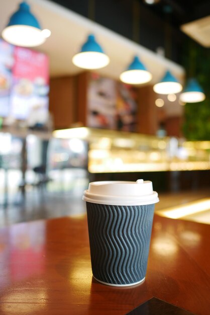 Nehmen Sie Papierkaffeetasse o auf dem Café-Tisch mit