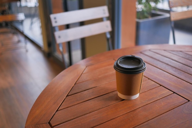 Nehmen Sie Papierkaffeetasse o auf dem Café-Tisch mit