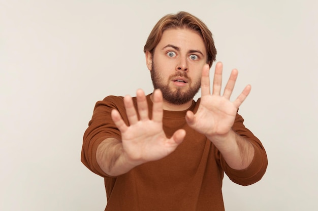 Nein, ich habe Angst Porträt eines in Panik geratenen, verängstigten Mannes mit Bart im Sweatshirt, der die Hände hebt, um etwas Schreckliches zu stoppen