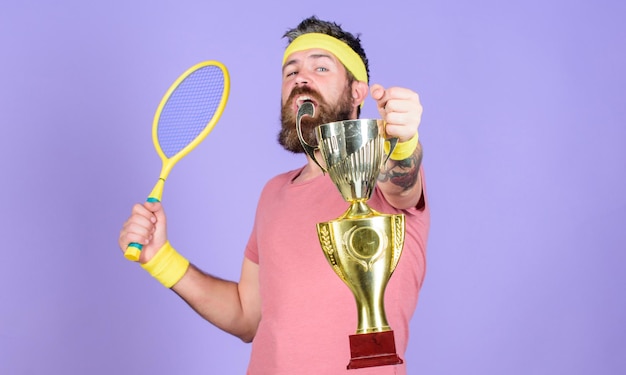 Nenhum jogador pode pisar na quadra contra mim e se sentir confiante Homem barbudo hipster usa roupa esportiva Jogador de tênis ganha campeonato Atleta hipster segura raquete de tênis e taça de ouro Vença o jogo de tênis