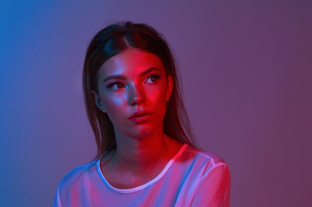 Neon Nahaufnahme Porträt der jungen Frau. Studioaufnahme. Model posiert in lila, roten und rosafarbenen Lichtern. Mode zurück in die 80er - 90er neues Trendkonzept.