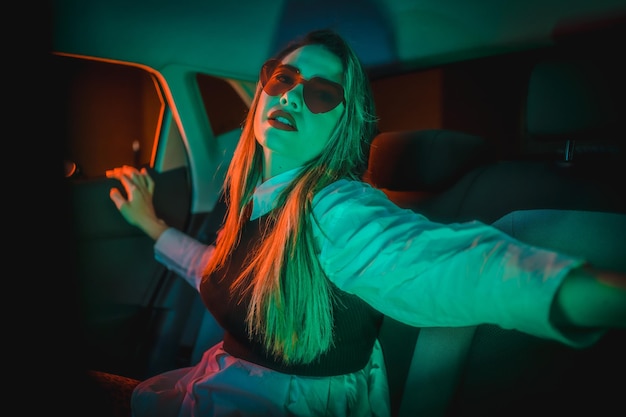 Neonfotografie in einem Auto einer jungen blonden Frau mit Herzbrille