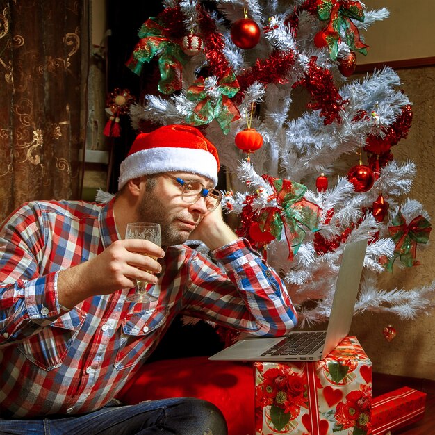 Nerd de Natal solitário com um laptop debaixo da árvore. Ano Novo. Espírito de natal.
