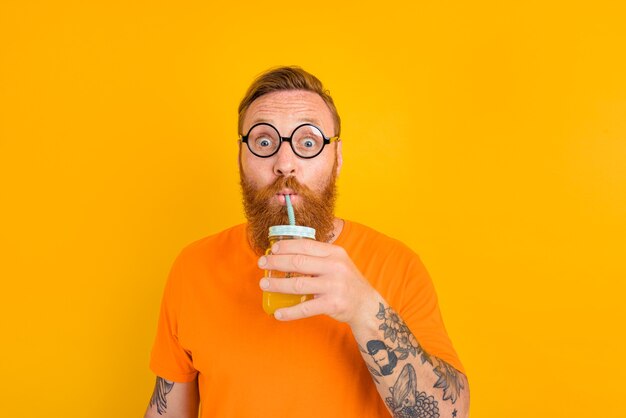 Nerd erstaunter Mann mit Brille trinkt einen Fruchtsaft
