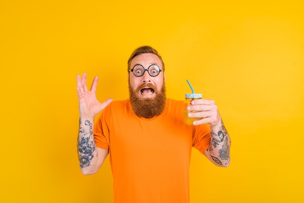 Nerd hombre asustado con gafas bebe un jugo de fruta