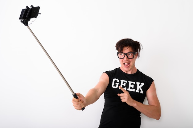 Nerd-Mann, der Foto mit Handy macht, das an Selfie-Stick befestigt ist