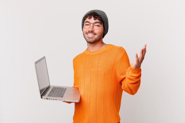 Nerd-Mann mit Computer, der sich glücklich, überrascht und fröhlich fühlt, mit positiver Einstellung lächelt und eine Lösung oder Idee realisiert