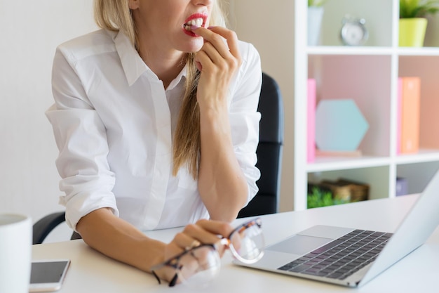 Nervöse Frau bei der Arbeit, die ihre Nägel beißt