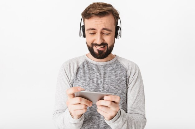 Foto nervöser aufgeregter junger mann spielt spiele per handy