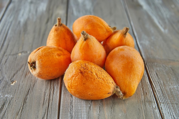 Nêsperas maduras Nêsperas frutas Grupo de nêsperas de frutas laranja japonesas ameixas doces suculentas exóticas em fundo de madeira