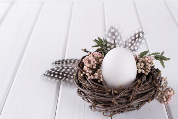 Nest mit weißem Hühnerei. Osterkonzept. Frohe Ostern oder Frühlingsgrußkarte