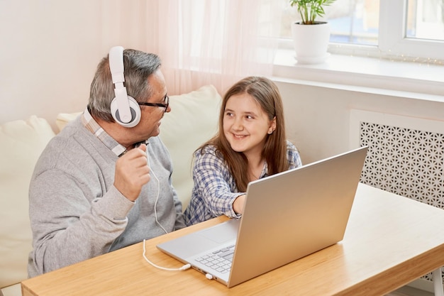 Neta ajudando vovô a fazer comunicação on-line no laptop