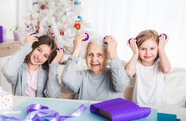 Netas sorridentes segurando bolas decorativas como olhos da vovó no natal