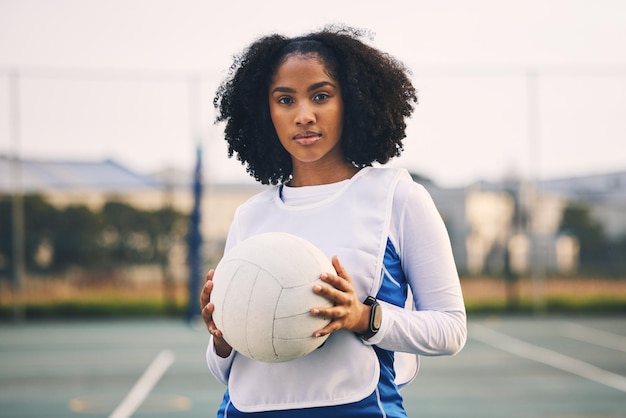Netball deportivo y retrato de una mujer con una pelota después de un ejercicio de partido o entrenamiento en la cancha Fitness de confianza y atleta capitana femenina de pie en el campo después de un entrenamiento o práctica de juego