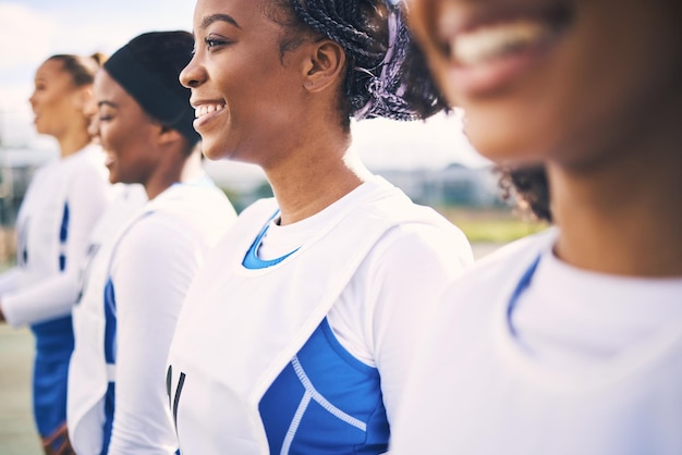 Netball esportivo e equipe de mulheres com sorriso pronto para exercícios de treinamento e exercícios físicos na quadra trabalho em equipe de diversidade e fila de atletas felizes com motivação para jogo e prática