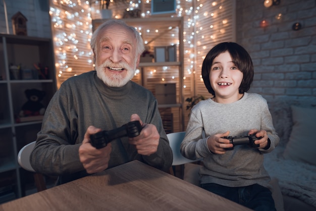 Neto de retrato jogar videogame com o avô