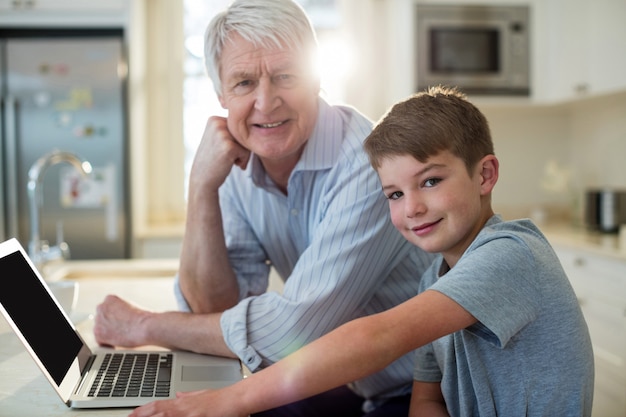 Neto e avô com laptop na cozinha