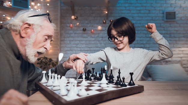 Neto e avô jogando xadrez juntos