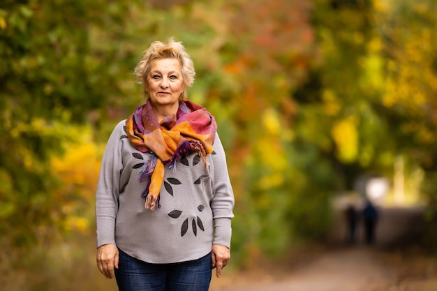 nette ältere frau steht auf einem hintergrund von gelbem herbst