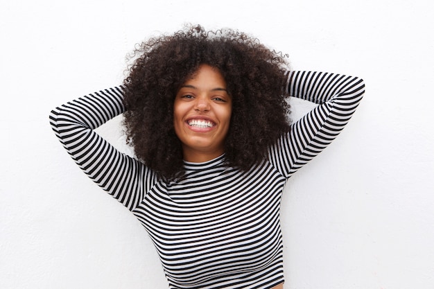 Nette Afroamerikanerfrau mit den Händen im lockigen Haar