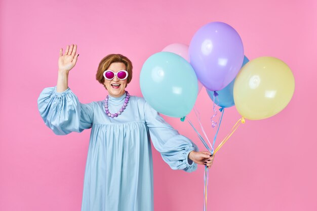 Nette alte Frau mit Luftballons im blauen Kleid