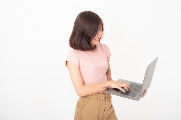 Nette asiatische jugendlich Frau arbeitet mit Computer auf weißer Wand