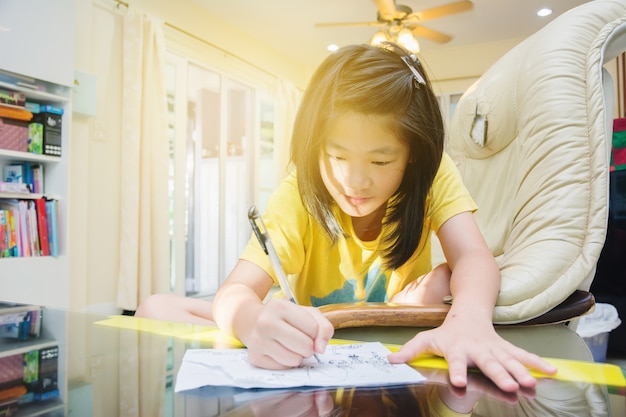 Nette asiatische Kinder, die zu Hause Karikatur am Morgen zeichnen