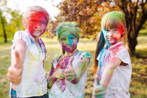 Nette europäische Kindermädchen feiern indisches Holi-Festival mit buntem Farbpulver auf Gesichtern und Körper