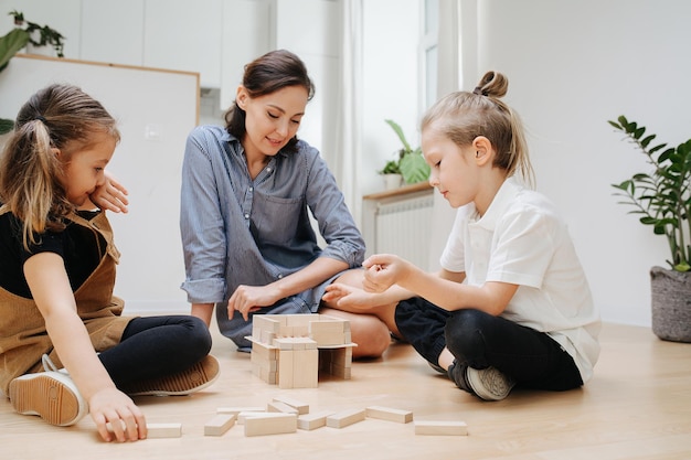 Nette Familie, die auf dem Boden mit Blöcken spielt Mama und zwei Kinder