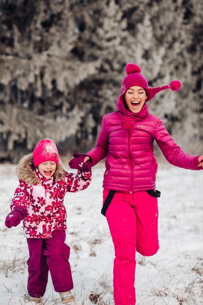 Nette Familie hat Spaß in einem Winterpark Mutter und Tochter spielen im Winter in warmer Kleidung haben Spaß Umarmung freuen sich Familientag