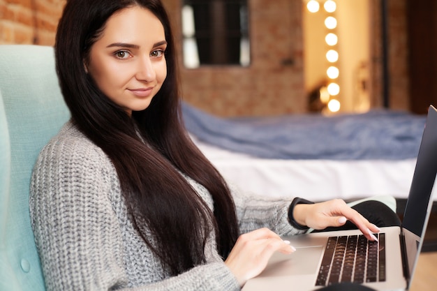 Nette Frau bleiben zu Hause und arbeiten am Laptop