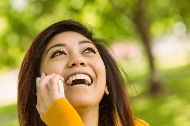 Nette Frau, die Handy im Park verwendet