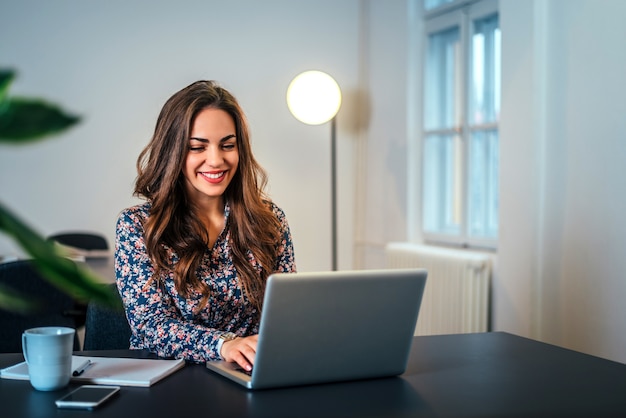 Nette Frau, die Laptop am Arbeitsplatz verwendet.