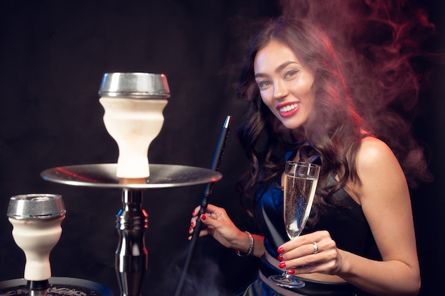 Nette Frau, die shisha raucht und Cocktail in einer Bar trinkt