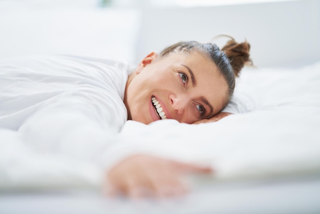 Nette Frau im Bett, die sich entspannt oder Yoga macht