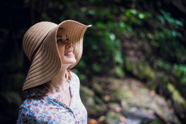 Nette Frau mit einem Hut, der im Wald aufwirft