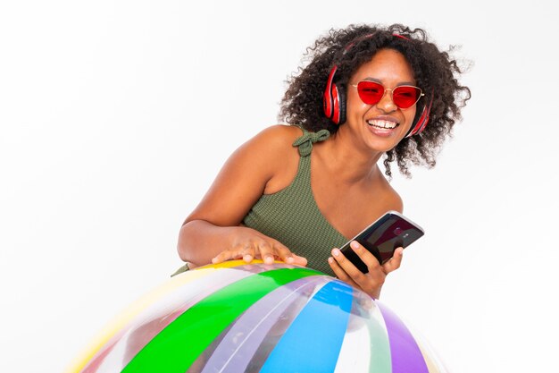 Nette Frau mit großen roten Kopfhörern, Sonnenbrille und Telefonständern mit großem Gummiball lokalisiert auf weißem Hintergrund