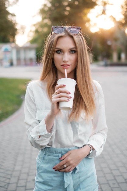 Nette Frau mit Sonnenbrille, die einen Milchshake trinkt