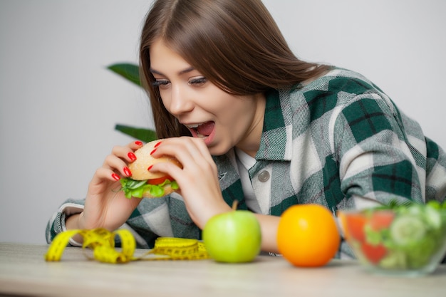 Nette Frau trifft eine Wahl zwischen gesundem und schädlichem Essen