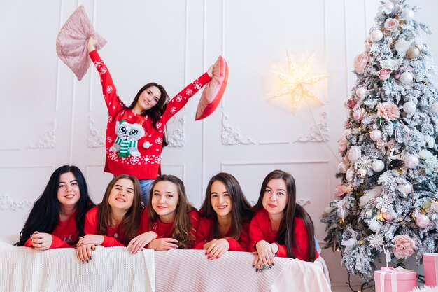 Nette Frauen mit roten Pullovern, die Weihnachten feiern