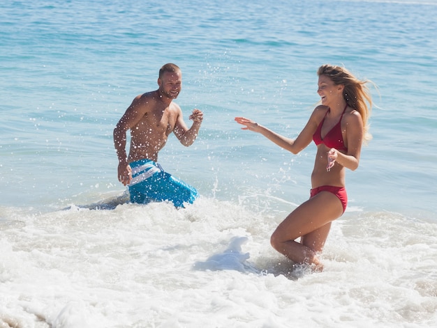 Nette Freunde, die miteinander Wasser im Meer werfen