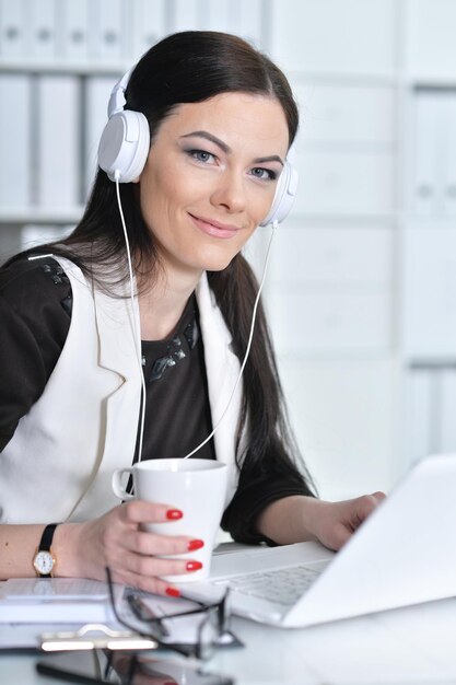 Nette Geschäftsfrau, die mit Laptop am Tisch sitzt