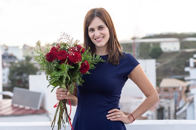 Nette glückliche junge Frau mit Blumenstrauß von roten Rosen